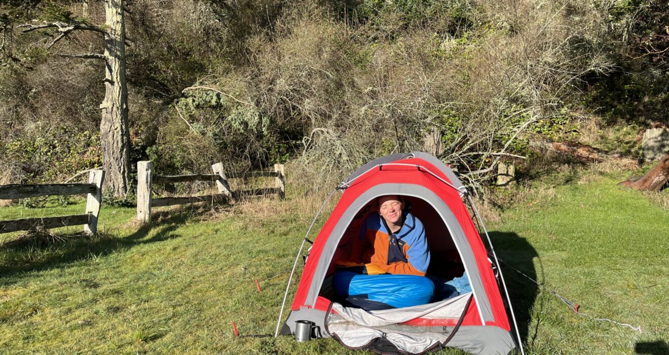 An edited polaroid of Barrett sitting in a tent with a caption stating, 