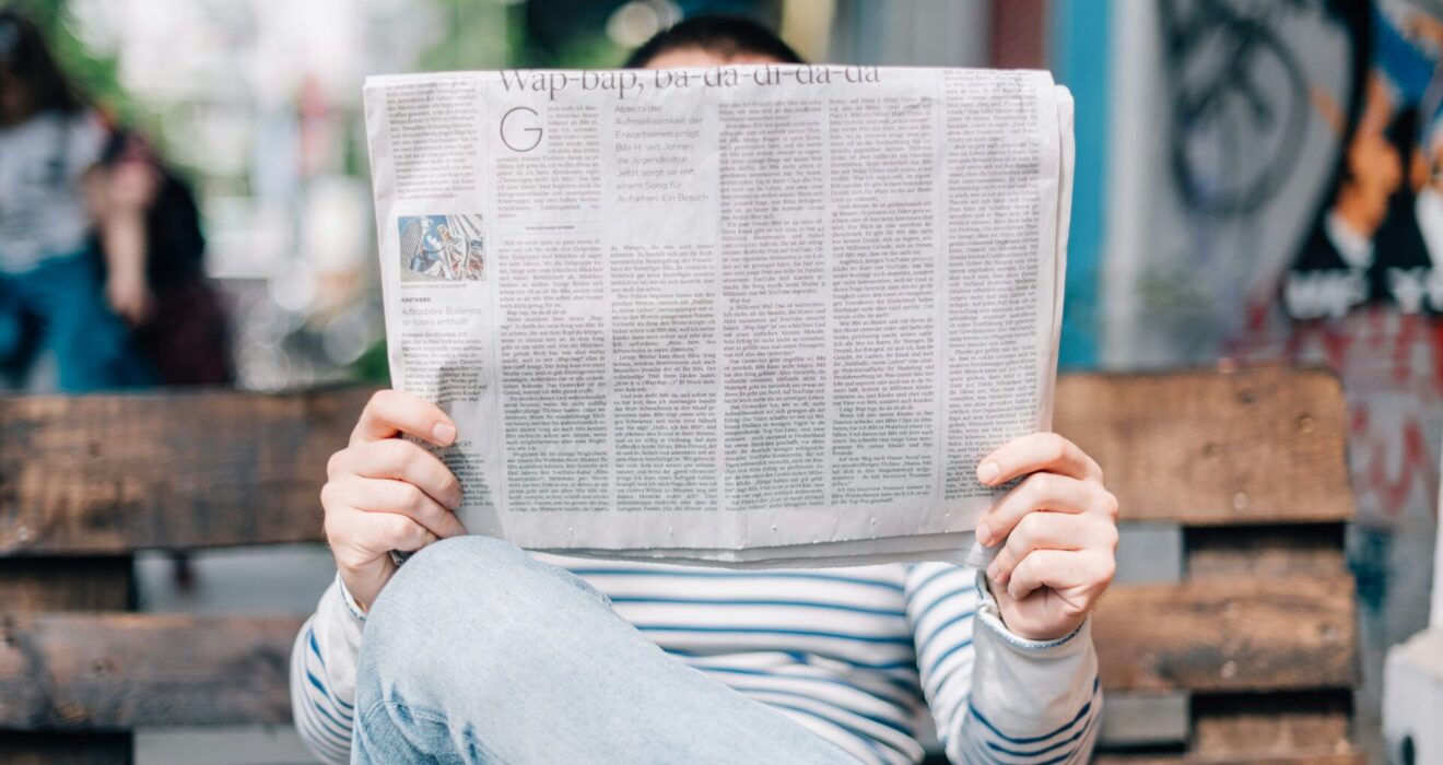 Person on a bench reading a newspaper