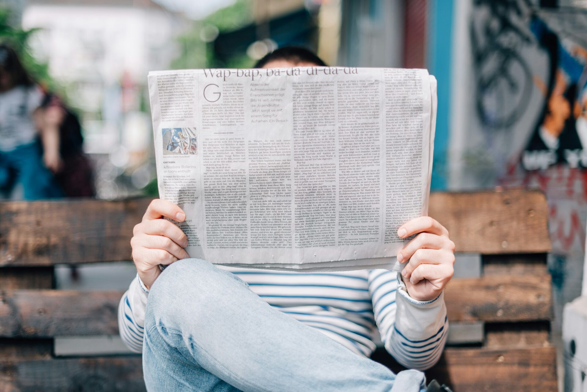 Person on a bench reading a newspaper