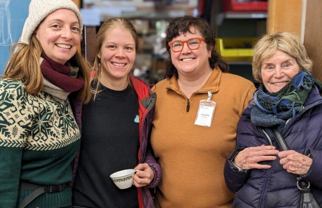 Four staff, volunteers, and community members are standing in the Workshop of the NE Seattle Tool Library during the open house to celebrate 12 years of tool lending.