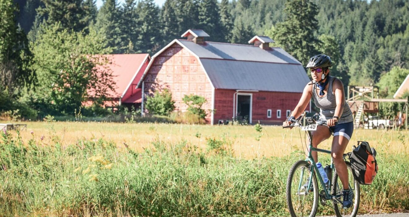Aakanksha participating in the Seattle to Portland Bike ride. Greenery and a barn are in the background.