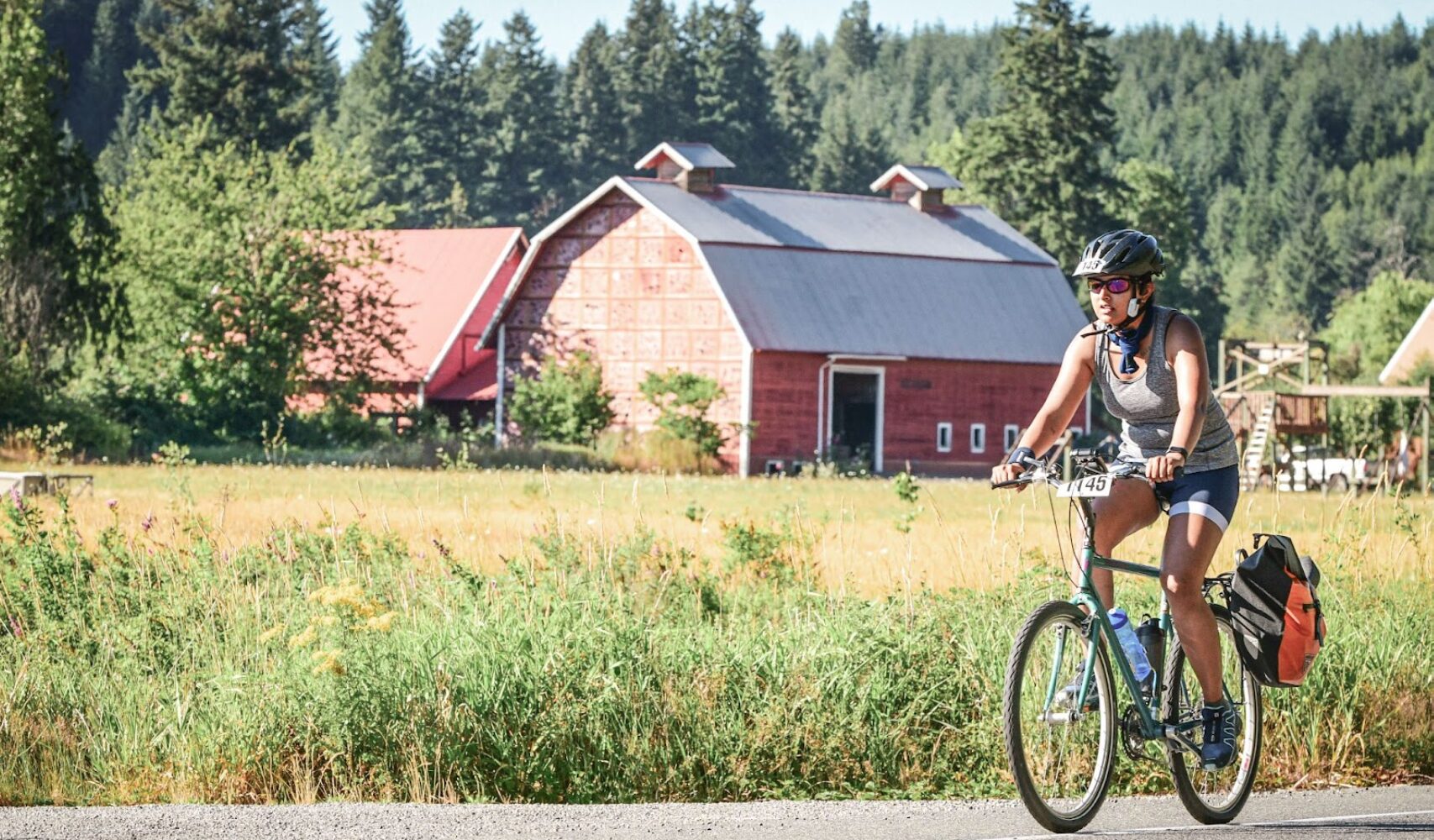 Aakanksha participating in the Seattle to Portland Bike ride. Greenery and a barn are in the background.
