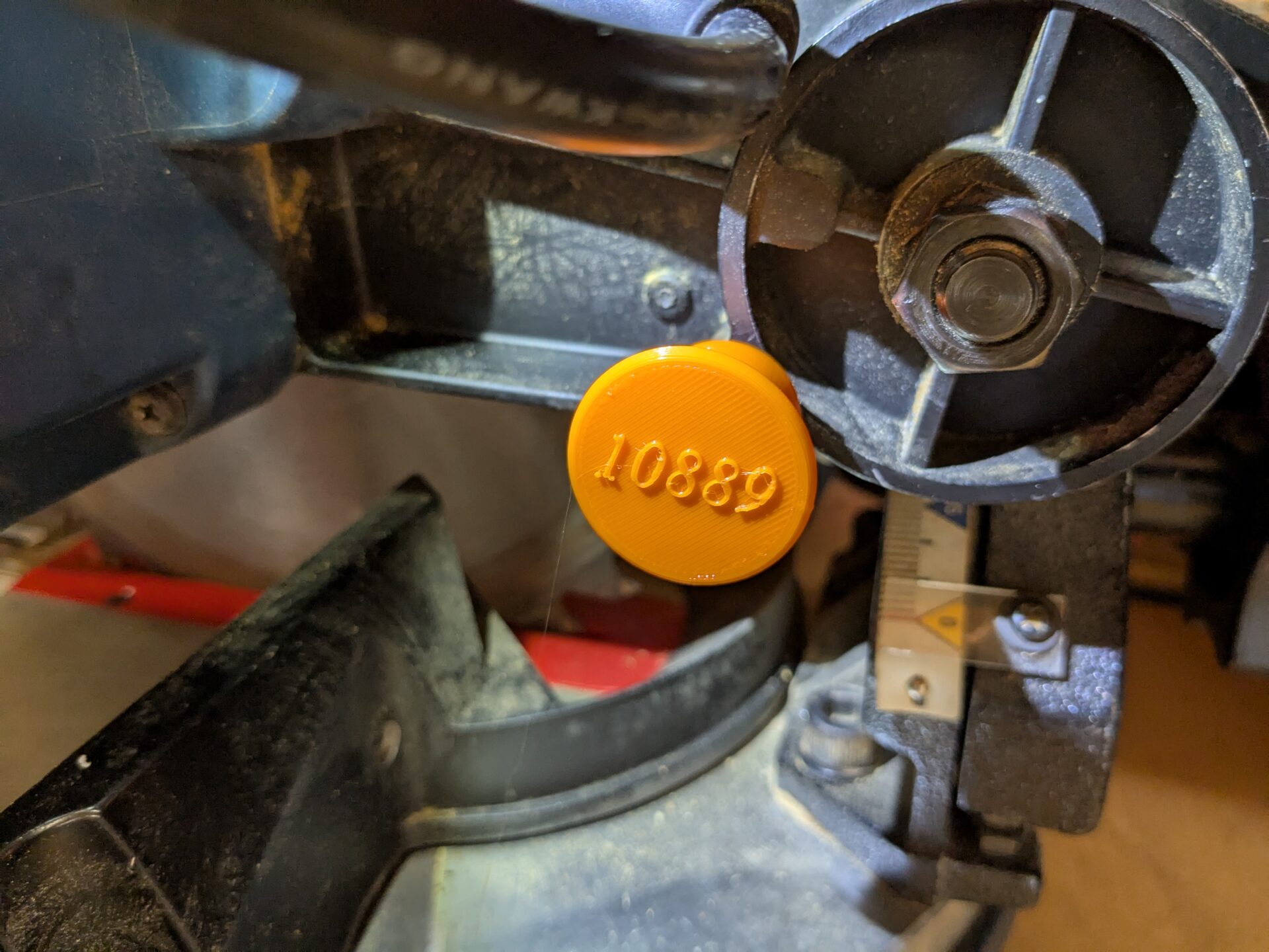 Orange 3D printed knob for miter saw.