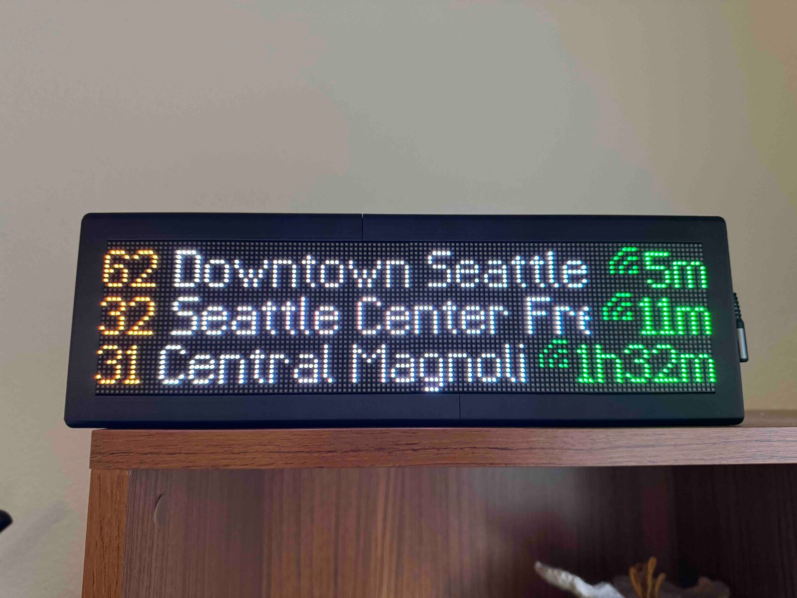 A closeup of a DIY public transit arrivals board. It shows a couple of different arrivals times for different buses around Seattle.
