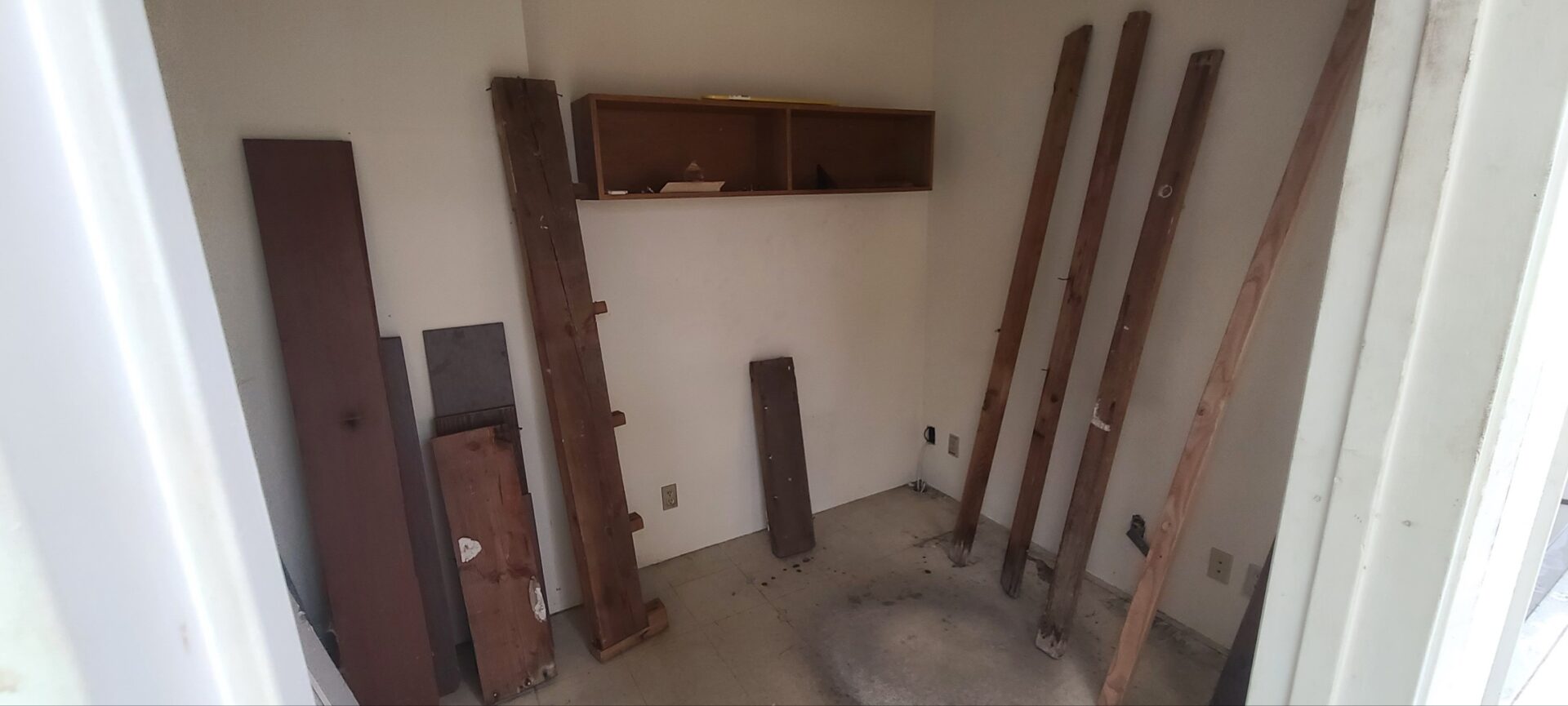 A small room that has wooden planks leaned up against walls.