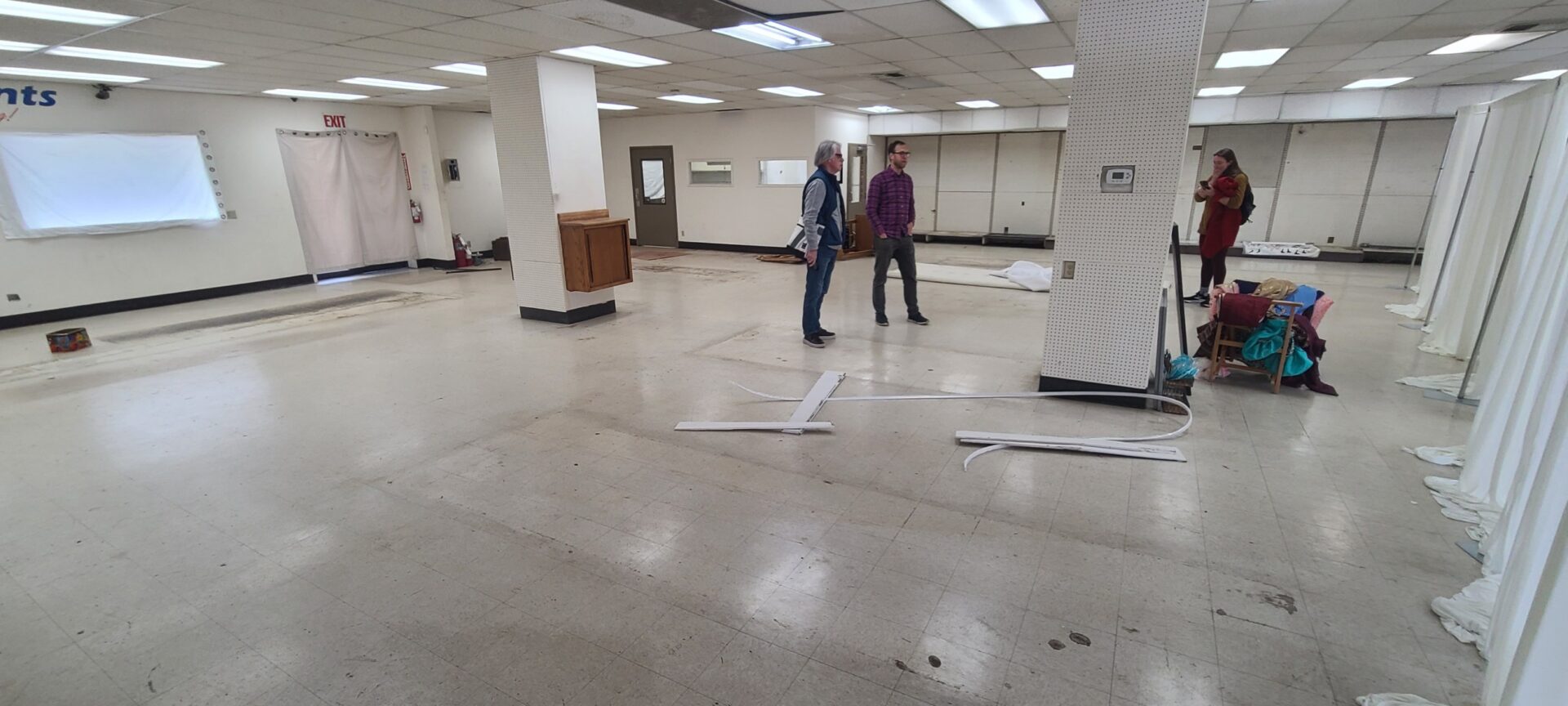 A couple of people chat with one another in the middle of an empty space.