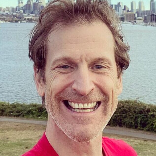 Brian Coles smiles at the camera in front of a skyline.