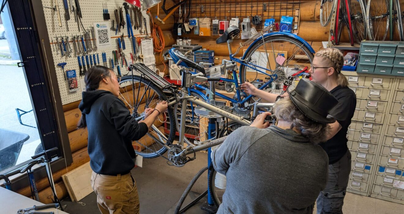 Three people work on a bike in the Shoreline Tool Library Bike Shack.
