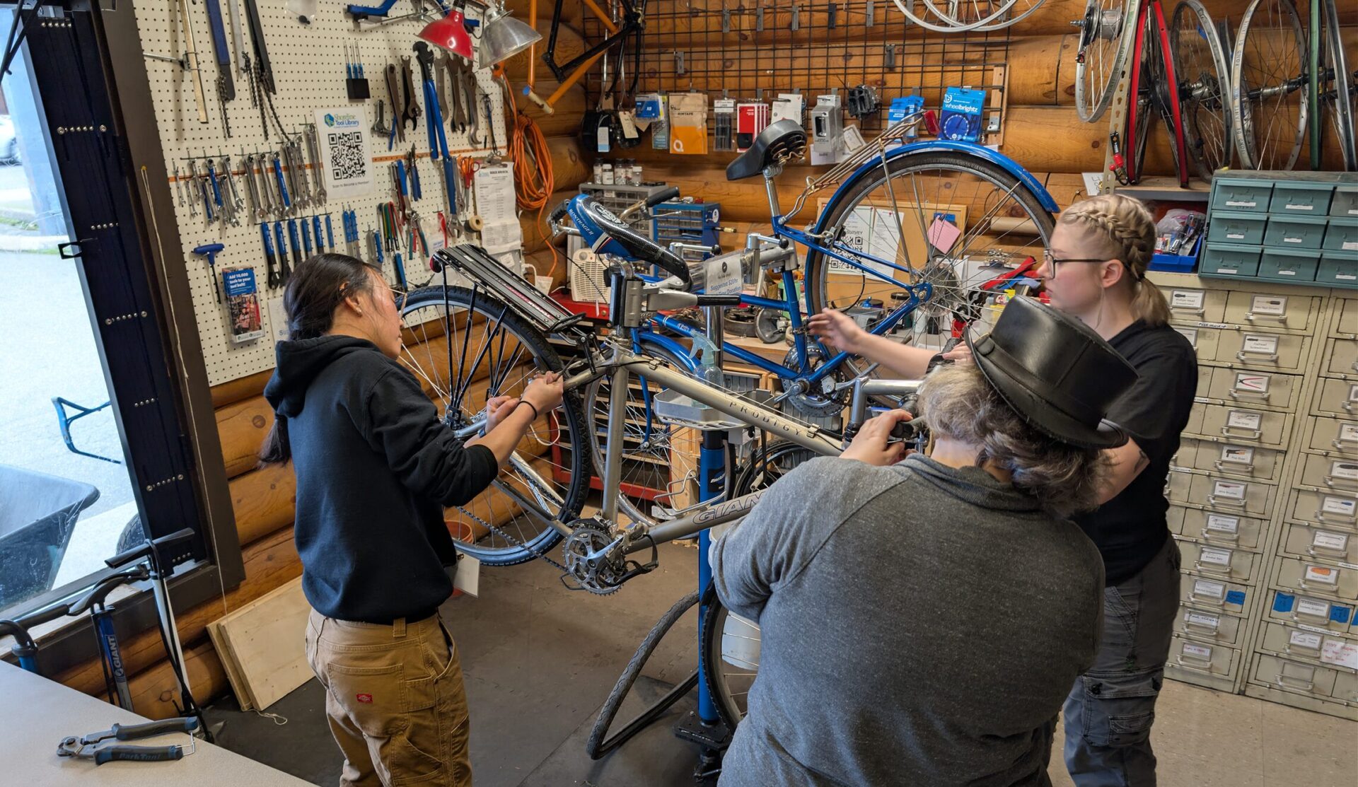 Three people work on a bike in the Shoreline Tool Library Bike Shack.